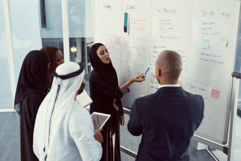 High angle shot of a group of diverse business colleagues working together on a whiteboard in their office